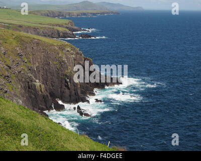 Sonnendurchflutetes Wellen gegen Felsen und Buchten des Slea Head auf der Halbinsel Dingle Irland mit blauem Meer und grünen Landzungen Stockfoto