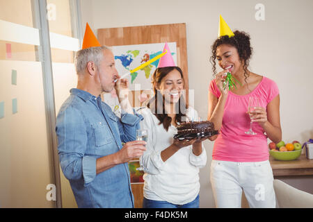 Kollegen, die Geburtstagsfeier der Geschäftsfrau Partei Horn bläst Stockfoto