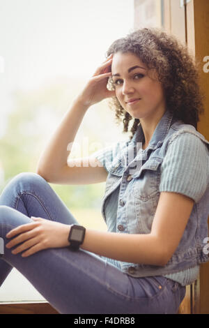 Hübsche Studentin Fenster in die Kamera Lächeln sitzen Stockfoto