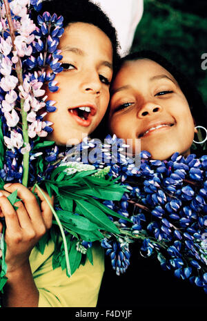 Ein Mädchen, 7 Jahre alt, und ein Junge, 8 Jahre alt, mit Blumen. Stockfoto