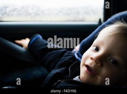 Ein einjähriger Junge in einem Autositz. Stockfoto