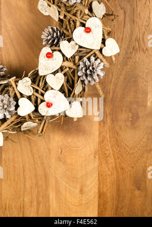 Handgemachte Vintage Kranz Weihnachtsdekoration Shabby Chic weiße Holzherzen mit roten Beeren über hölzerne Hintergrund - Retro-Stil Stockfoto