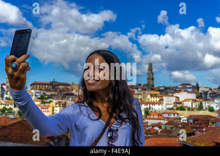 Schöne Frau nimmt ein Selbstporträt mit einem Smartphone mit dem Hintergrund der alten Stadt Porto. September 2015. Porto, Portugal. Stockfoto