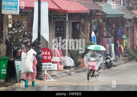 Sapa oder Sa Pa ist eine Grenzstadt in Nord-West-Vietnam, Aufnahmen hier in der Regenzeit feucht als Fahrer trägt Regenschirm auf Roller Stockfoto