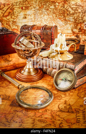 Vintage Stillleben. Vintage Lupe Lügen, Taschenuhr, altes Buch und Armillarsphäre auf einer antiken Welt Karte im Jahre 1565. Stockfoto