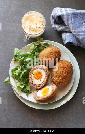 Scotch Eiern auf einem Teller mit Brunnenkresse-Salat und Mayonnaise-dip Stockfoto