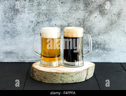 Helles und dunkles Bier im Becher auf Holzbrett, Grunge Hintergrund Stockfoto