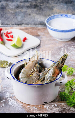 Zutaten für würzige Thai Suppe Tom Yam Kokosmilch, Chili Peppers, Shiitake Pilzen und Garnelen in Keramikschalen über Stein Stockfoto