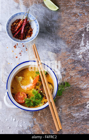 Weiße Keramik Pfanne mit würzigen Thai Suppe Tom Yam mit Kokosmilch, Chili-Pfeffer und Garnelen auf grauem Stein Hintergrund. Mit woode Stockfoto