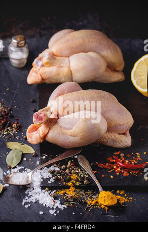 Zwei Raw Mini Huhn mit Meer-Salz und verschiedenen Gewürzen über Schiefer Tafel Stockfoto