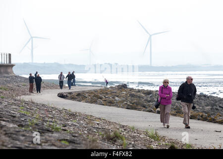 Menschen Fuß auf einem Wanderweg neben Bristol-Kanal in der Nähe von Avonmouth Docks und Windkraftanlage an der Severn Strand Bridge in der Nähe von Bristol Stockfoto
