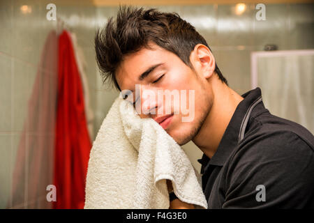 Junger Mann trocknen Gesicht mit Handtuch als Teil der täglichen Hygiene-Routine Stockfoto