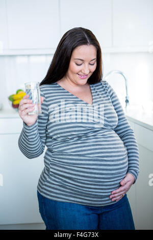 Schöne schwangere Frau berühren ihren Bauch ein Glas Wasser zu trinken Stockfoto