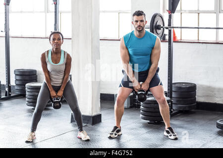 Ein muskulöser paar Kettlebells heben Stockfoto