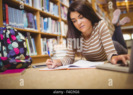 Porträt von Studentin Multitasking liegend am Boden Stockfoto