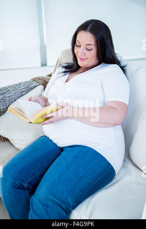 Süße schwangere Frau ein Buch auf der couch Stockfoto