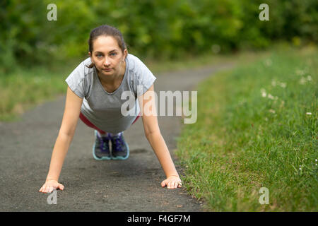 Junge Mädchen tun Warm-up im Park. Drücken Sie aus dem Boden. Stockfoto