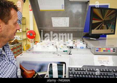 Mann arbeitet in Paint Shop unter Farbe mischen Industriemaschine. Niederlande. Stockfoto