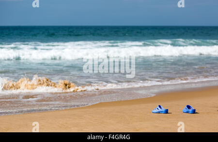 Blaue Damenschlappen am Meer Sandstrand, Sommer Urlaub Konzept Stockfoto