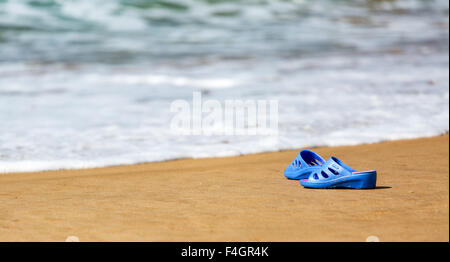 Blaue Damenschlappen am Meer Sandstrand, Sommer Urlaub Konzept Stockfoto