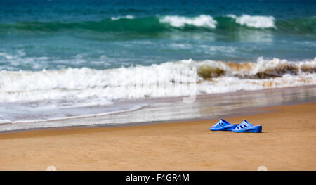 Blaue Damenschlappen am Meer Sandstrand, Sommer Urlaub Konzept Stockfoto