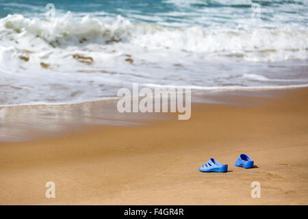 Blaue Damenschlappen am Meer Sandstrand, Sommer Urlaub Konzept Stockfoto