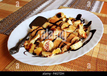 Pfannkuchen gefüllt mit Grieß, Bananen und Orangen getränkt dunklen Schokolade Stockfoto