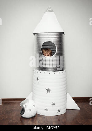Glückliches Kind gekleidet in ein Astronaut Kostüm mit handgefertigten Rakete spielen. Stockfoto