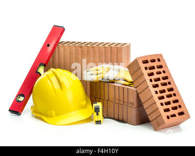 Gelochte Ziegel, gelben Helm, Schutzhandschuhe und Wasserwaage isoliert auf weiss Stockfoto