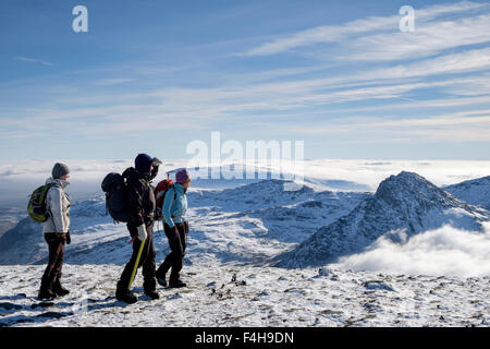 Drei Wanderer Wandern auf Pen Jahr Ole Wen Gipfel mit Aussicht auf den Berg oberhalb der niedrigen Tryfan Cloud im Winter in den Bergen von Snowdonia (Eryri) Wales UK Stockfoto