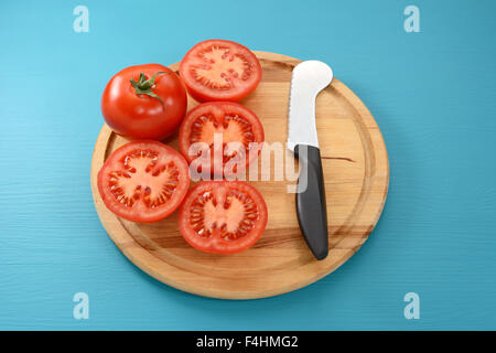 Ganze Tomaten und vier abgeschnittenen Hälften mit einem Tomaten-Messer auf einem Holzbrett Stockfoto