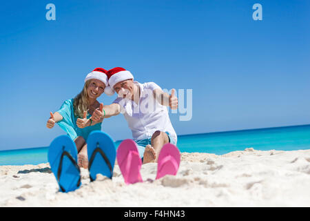 Karibik Weihnachten Urlaub am sandigen Strand. Zwei paar Flip flops stehen in einem Sand auf Hintergrund mit emotionalen paar Stockfoto