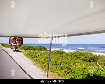 Touristen reiten Golf-Carts auf Rueda Medina, verläuft eine Hauptstraße, die von Playa Norte nach Punta Sur in Isla Mujeres, Mexiko Stockfoto