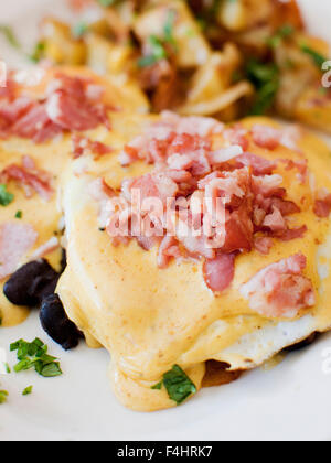 Caribbean Style Eggs Benedict mit pochierten Eiern auf einem Bett aus Bananen, Käse und schwarzen Bohnen. Mango Cafe, Isla Mujeres Stockfoto