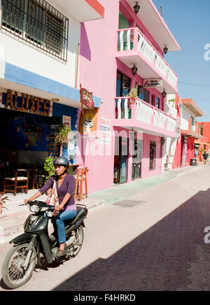 Eine Mexikanerin fährt ein Moped durch die Innenstadt von Isla Mujeres. Isla Mujeres, Quintana Roo, Mexiko. Stockfoto