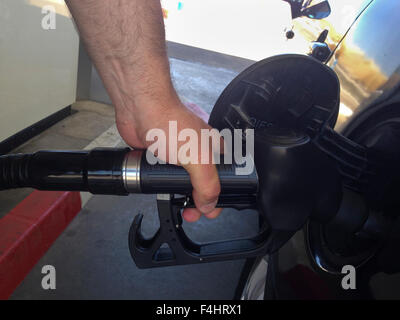A mans Hand füllt Benzin auf ein schwarzes Auto Stockfoto