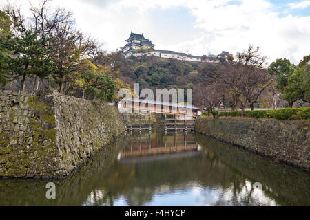 Japan, Wakayama Castle. Rekonstruierte Ohashiroka Brücke, ein seltenes Beispiel für eine überdachte geschlossene Brücke über den Burggraben, die Hügel im Hintergrund halten. Stockfoto