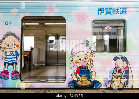 Iga Ueno, Japan. Kintetsu private Eisenbahn, Iga Tetsudo, Iga-Linie. Zug - carraige auf der Außenseite mit cartoon Kinder durch offene Wagen Tür eingerichtet. Stockfoto