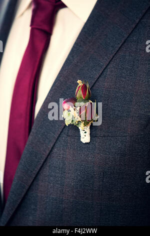 Rosenbusch Boutonniere an Bräutigams grauen Anzug Stockfoto