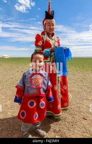 Frau und Kind in traditioneller Tracht (Deel), silberne Schale für Milch Gruß, in der Nähe von Ger, Gobi Wüste, Bulgan, Omnogov, Mongolei Stockfoto