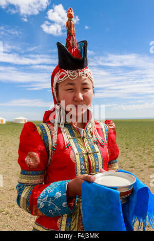 Frau in rot Deel und Zipfelmütze mit silbernen Schüssel Milch willkommen Besucher, Wüste Gobi, in der Nähe von Bulgan, Omnogov, Mongolei Stockfoto