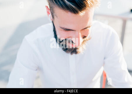 Porträt eines jungen schönen kaukasischen blonde modernen Geschäftsmann auf der Suche nach unten, lächelnd - Glück, erfolgreiches Konzept Stockfoto