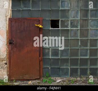 Alte im Alter Gebäude Fragment, zerstörten Haus. Fragment alte geschlossene Fabrik. Alte verlassene Türen mit selektiven Fokus. Zerstörten bauen Stockfoto