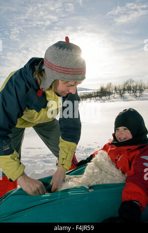 Mutter und Sohn Rodeln im Freien im Schnee Stockfoto