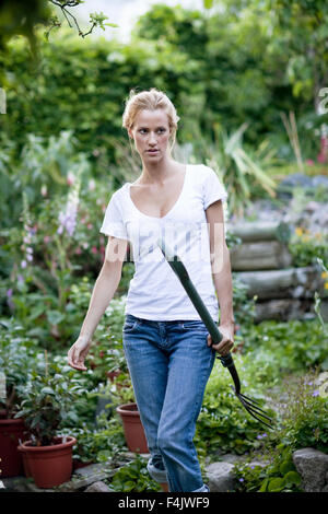 Junge Frau, die Heugabel im Garten Stockfoto