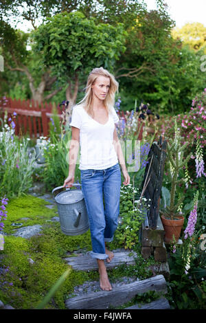 Junge Frau, die die Bewässerung kann im Garten Stockfoto