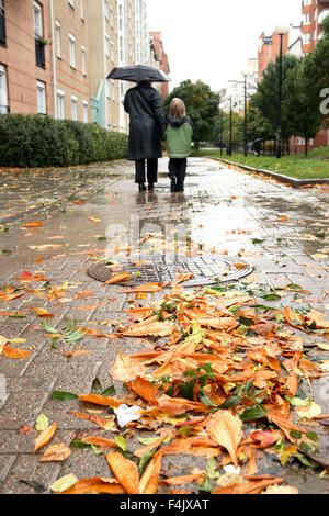 Mutter und Sohn zu Fuß durch Pflaster bei Regen Stockfoto
