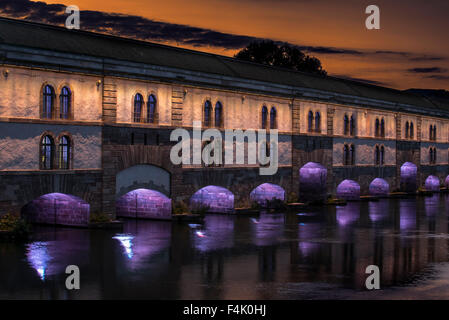 Beleuchtung bei Sonnenuntergang von der Barrage Vauban / Vauban-Wehr über den Fluss Ill in Straßburg, Elsass, Frankreich Stockfoto