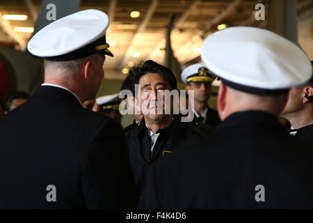 Der japanische Premierminister Shinzo Abe, Center, Plays als Captain Christopher Bolt, links, von der US Navy Nimitz-Klasse nuklearen Flugzeugträger USS Ronald Reagan erklären Betriebsabläufe an Bord bei einem Rundgang durch die Hangarbucht 18. Oktober 2015 in der Bucht von Tokio, Japan. Stockfoto