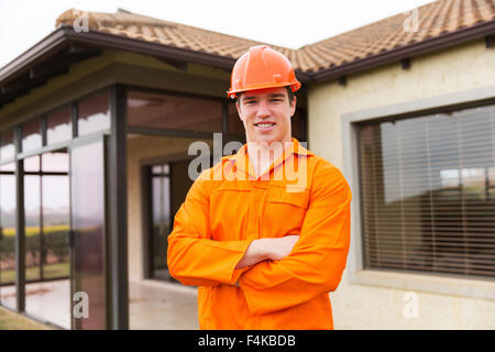 junge Bauarbeiter mit verschränkten vor einem Haus Stockfoto